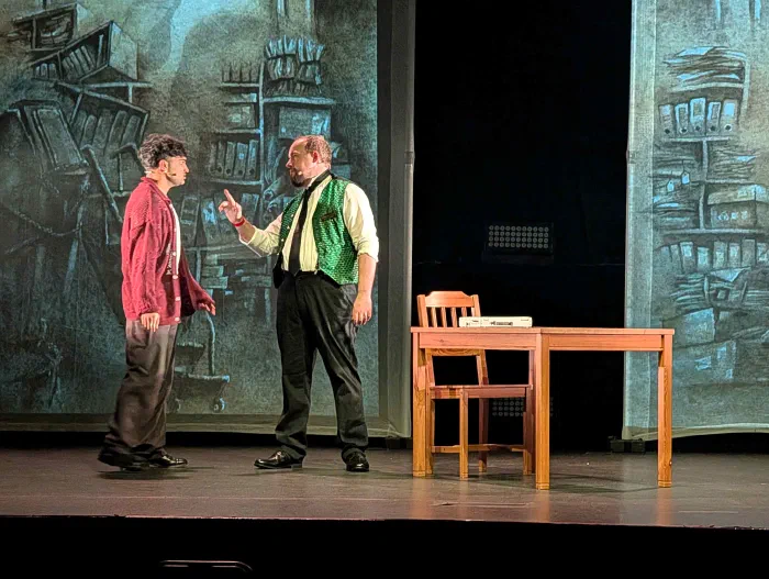 Rehearsal photograph for The Hilltop — Shahan Hamza and Jonathan Sims on stage in front of a large archive backdrop.