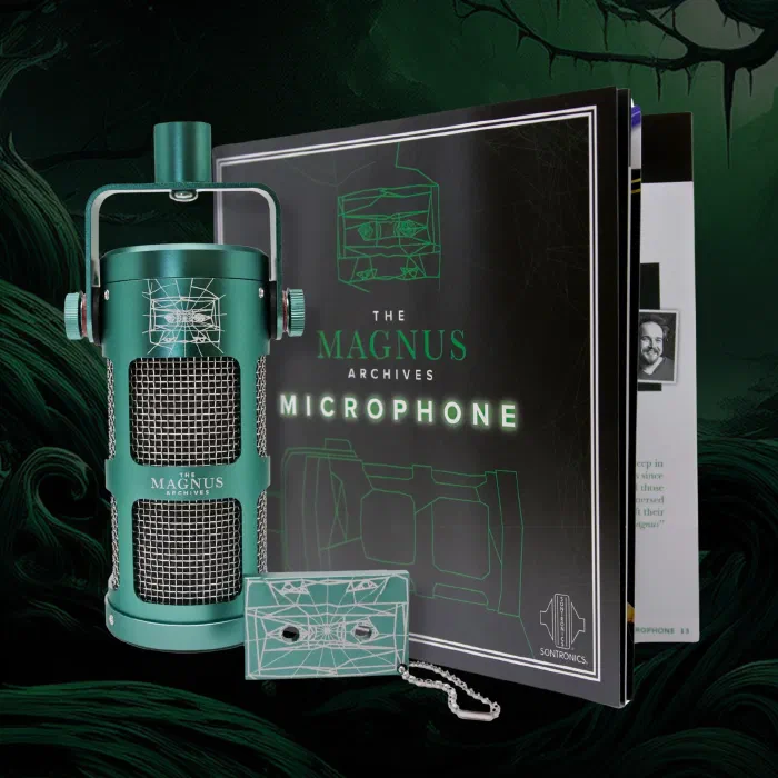 A photograph of a green microphone engraved with The Magnus Archives logo. Next to the mic is a large booklet and a cassette tape keychain. 